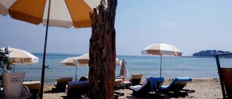 A beach with multiple umbrellas and lounge chairs.