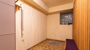 En bastu med ett rutmönstrat golv, en bänk, ett fönster med frostat glas och träväggar.
