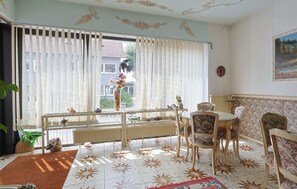 Ein Essbereich mit Tisch, Stühlen, einer Heizung und einem Fenster mit Vorhängen.