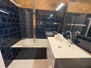Ein modernes Badezimmer mit einer gläsernen Dusche, einem weißen Waschbecken und einem Spiegel.