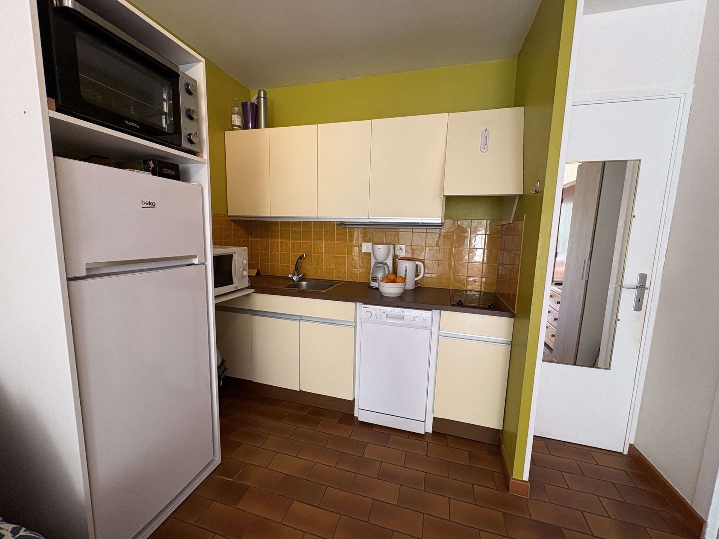A compact kitchen with a refrigerator, microwave, sink, and dishwasher.