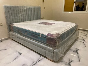 Una cama con cabecera, colchón y estructura de madera.