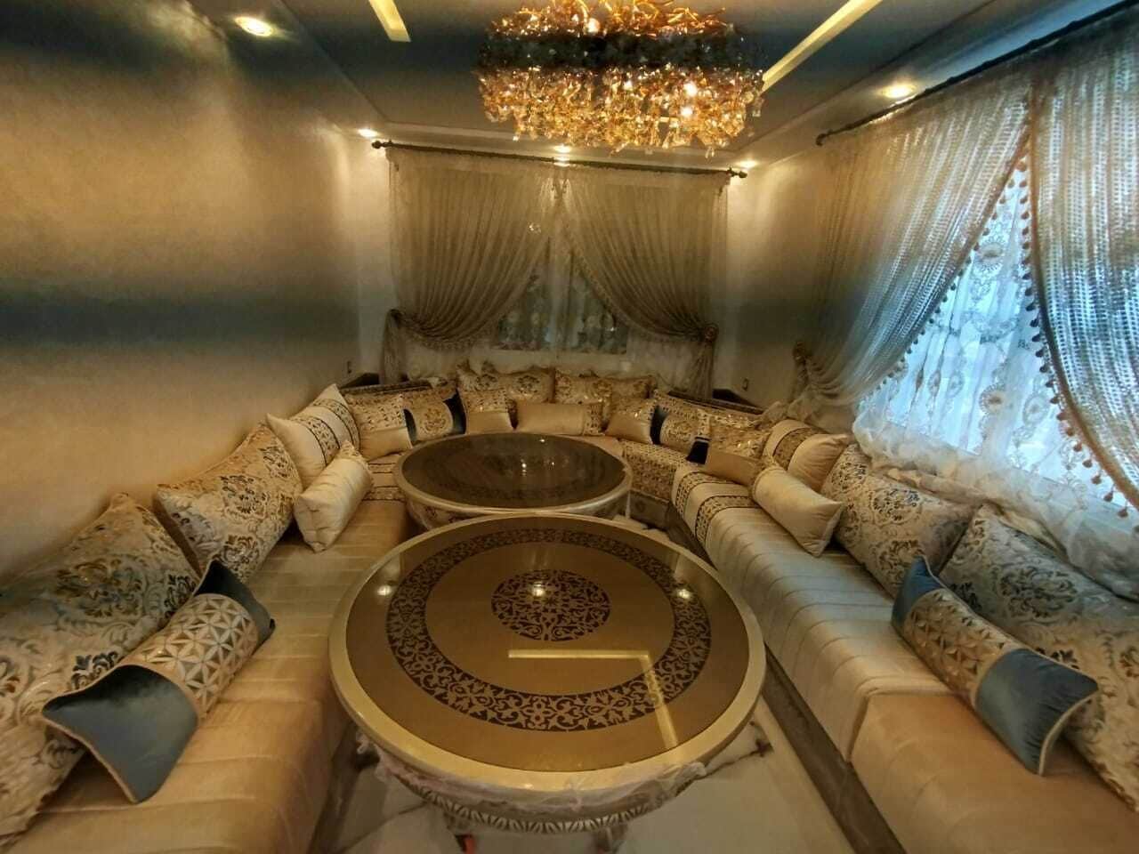 Ein luxuriöses Wohnzimmer mit einer Sofagarnitur, zwei runden Couchtischen und einem Chandelier.