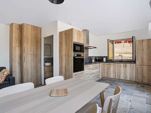 A modern kitchen with wooden cabinetry, a dining table, and a window with a view. - Renovated apartment mountain view - 2 guests (Saint-Pée-sur-Nivelle)