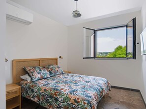 A bedroom with a bed, a window with an open view, a ceiling fan, and a wall-mounted air conditioner. - Renovated apartment mountain view - 2 guests (Saint-Pée-sur-Nivelle)