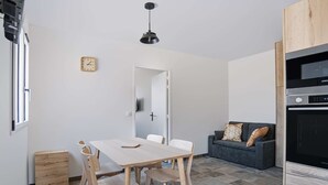A modern kitchen with a dining table and chairs, a sofa, and a clock on the wall. - Renovated apartment mountain view - 2 guests (Saint-Pée-sur-Nivelle)