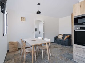 A modern kitchen with a dining table and chairs, a sofa, and a clock on the wall. - Renovated apartment mountain view - 2 guests (Saint-Pée-sur-Nivelle)