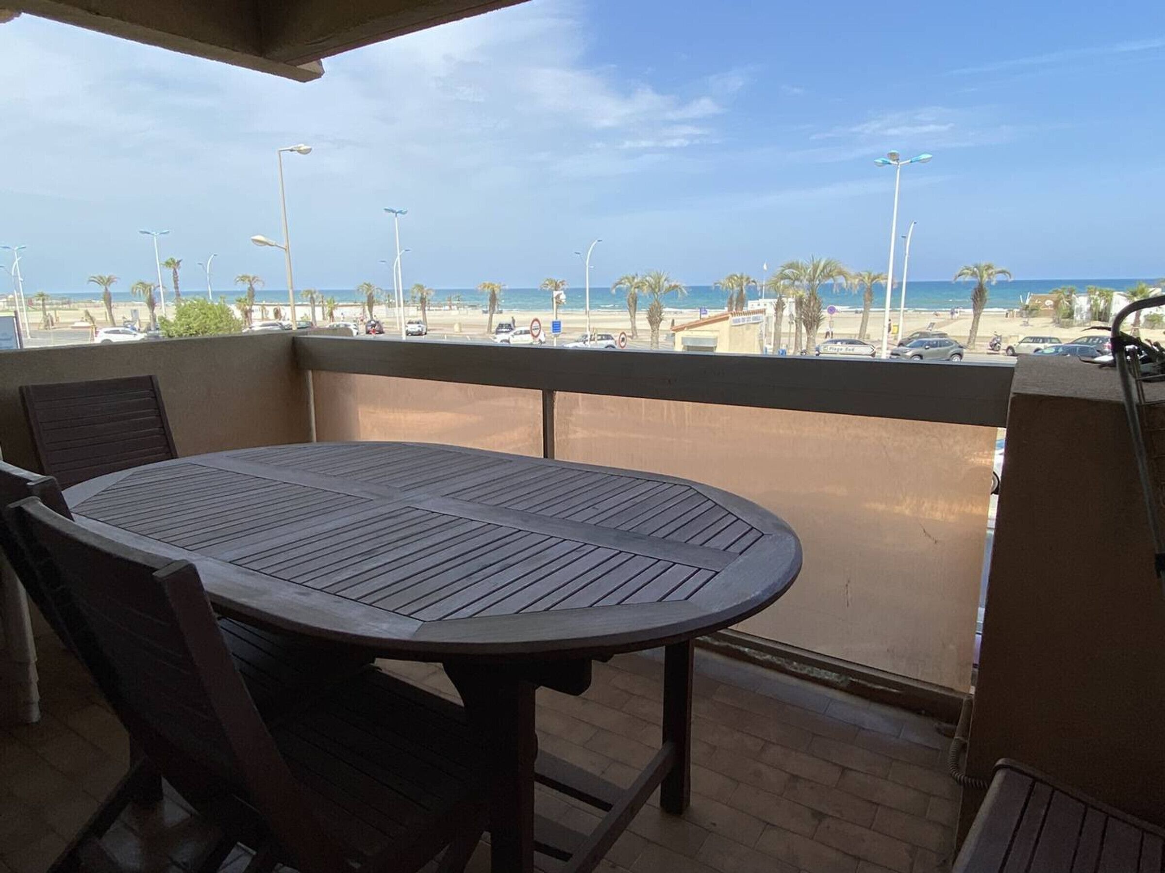 A balcony with a table and chairs overlooking a beach.