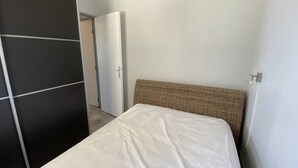 Een slaapkamer met een bed, een kledingkast en een deur naar een andere kamer.