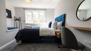 A bedroom with a bed, a chair, a desk, a mirror, and a window. - Relaxing Riverside Retreat (Gainsborough)