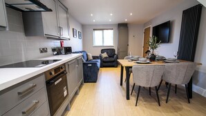A modern kitchen with built-in appliances, a dining area with a table and chairs, and a living space with a sofa. - Relaxing Riverside Retreat (Gainsborough)