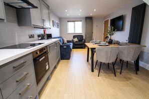 A modern kitchen with built-in appliances, a dining area with a table and chairs, and a living space with a sofa. - Relaxing Riverside Retreat (Gainsborough)