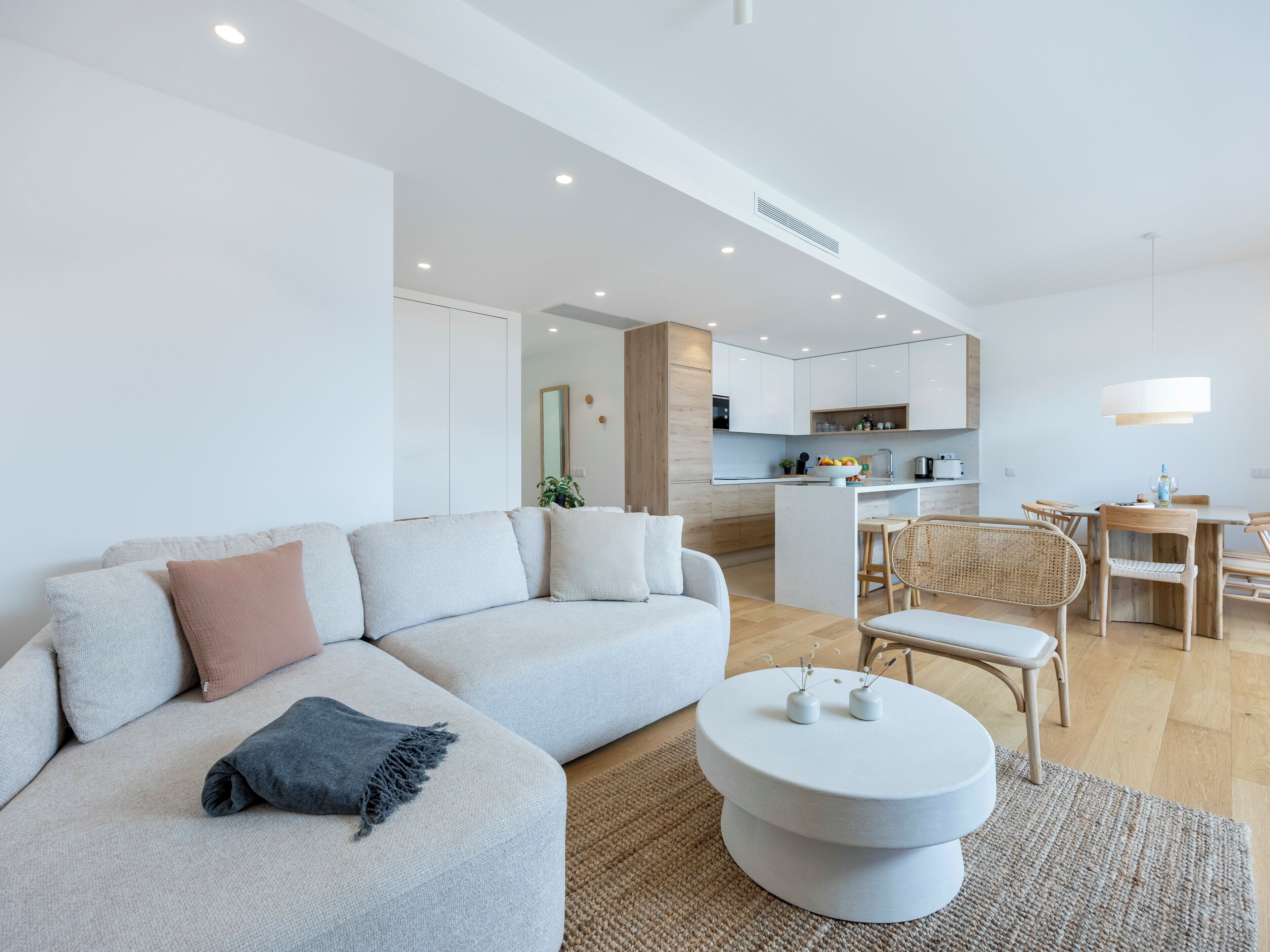 Ein modernes Wohnzimmer mit einer Couch, einem runden Couchtisch und einem Essbereich mit Stühlen und einem Tisch.