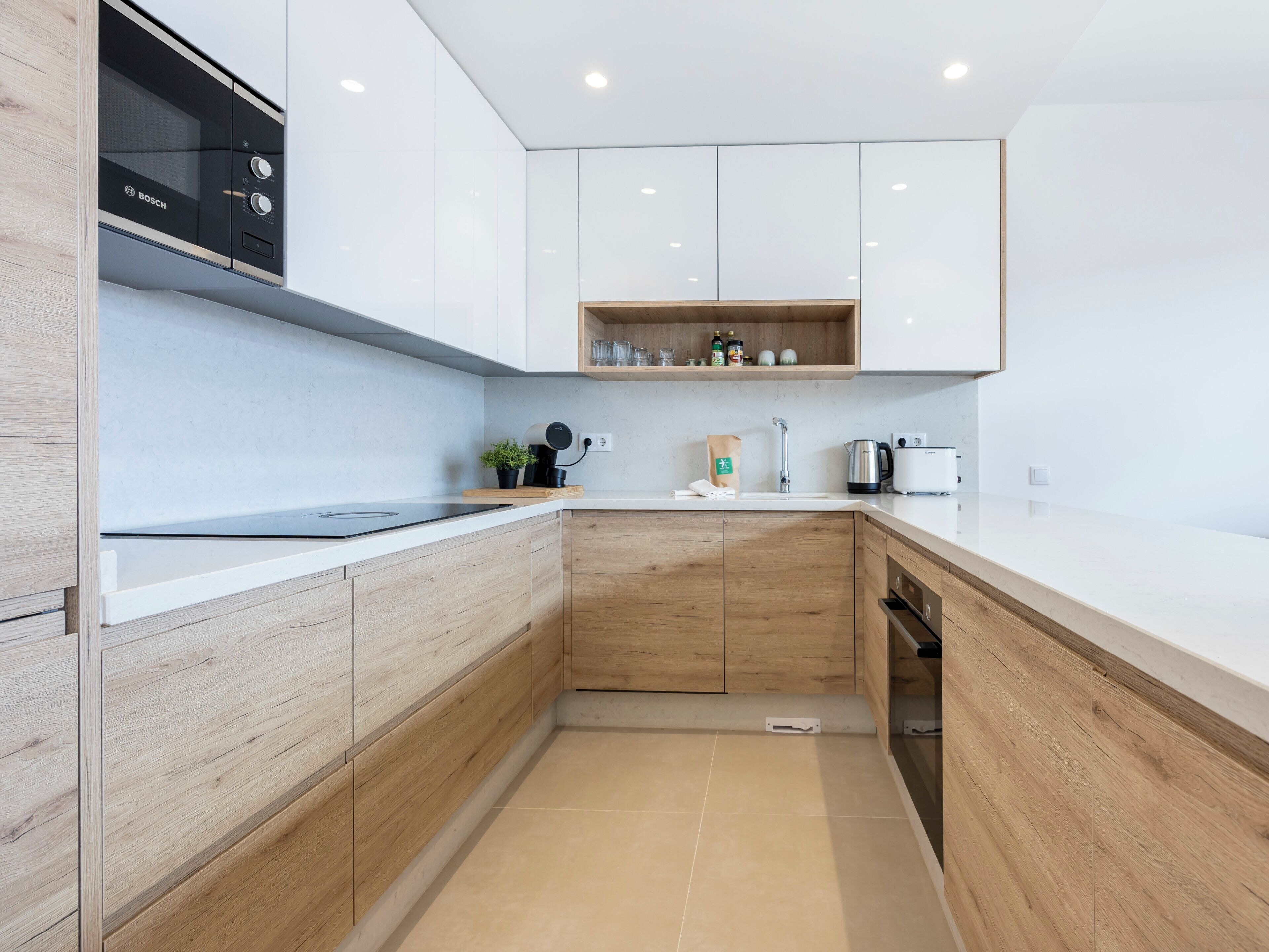 A modern kitchen with white cabinets, a Bosch microwave, a coffee machine, and a kettle.