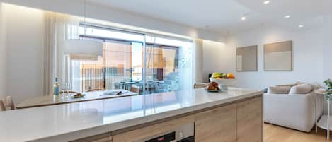 A modern kitchen with a built-in oven, a dining area with a table and chairs, and a staircase leading to an upper level.