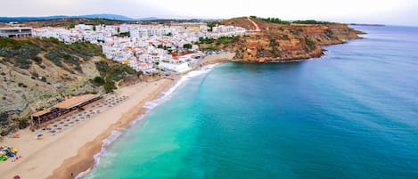 Un pueblo costero con playa, edificios y un acantilado.