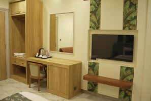 Quarto com escrivaninha de madeira, uma cadeira, uma cama, televisão e guarda-roupa.