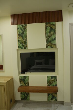 Ein Zimmer mit an der Wand montiertem Fernseher, Holzvertäfelung und Wandgestaltung mit Blattmuster.