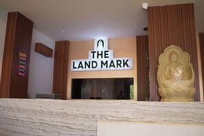 Uma área de recepção com uma placa indicando 'THE LAND MARK' e uma estátua de Buda.