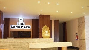 A reception desk with a sign reading 'THE LAND MARK,' a golden statue, and a fire extinguisher on the wall.