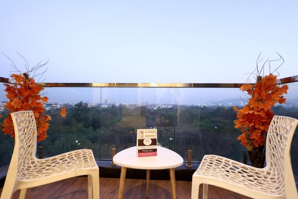A balcony with two wicker chairs, a small table, and a sign.