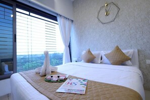 Ein Hotelzimmer mit einem großen Bett, einem Fenster mit Jalousien, einer Uhr an der Wand und einer Willkommensbroschüre auf dem Bett.