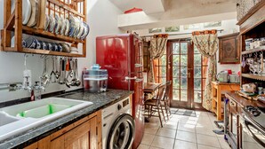 Een keuken met een wasmachine, een koelkast en een eethoek met een tafel en stoelen.
