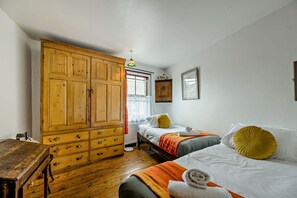 Ein Zimmer mit zwei Betten, einem Holzschrank, einem Heizkörper und einem fenster mit Vorhängen.