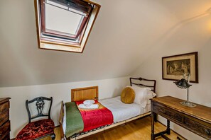 A room with a single bed, a wooden desk, a chair, a framed picture on the wall, and a skylight. - Host & Stay | The 1890 Petersfield Retreat (Cambridge)