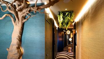 A hallway with a large tree sculpture, patterned floor, and a hanging plant.