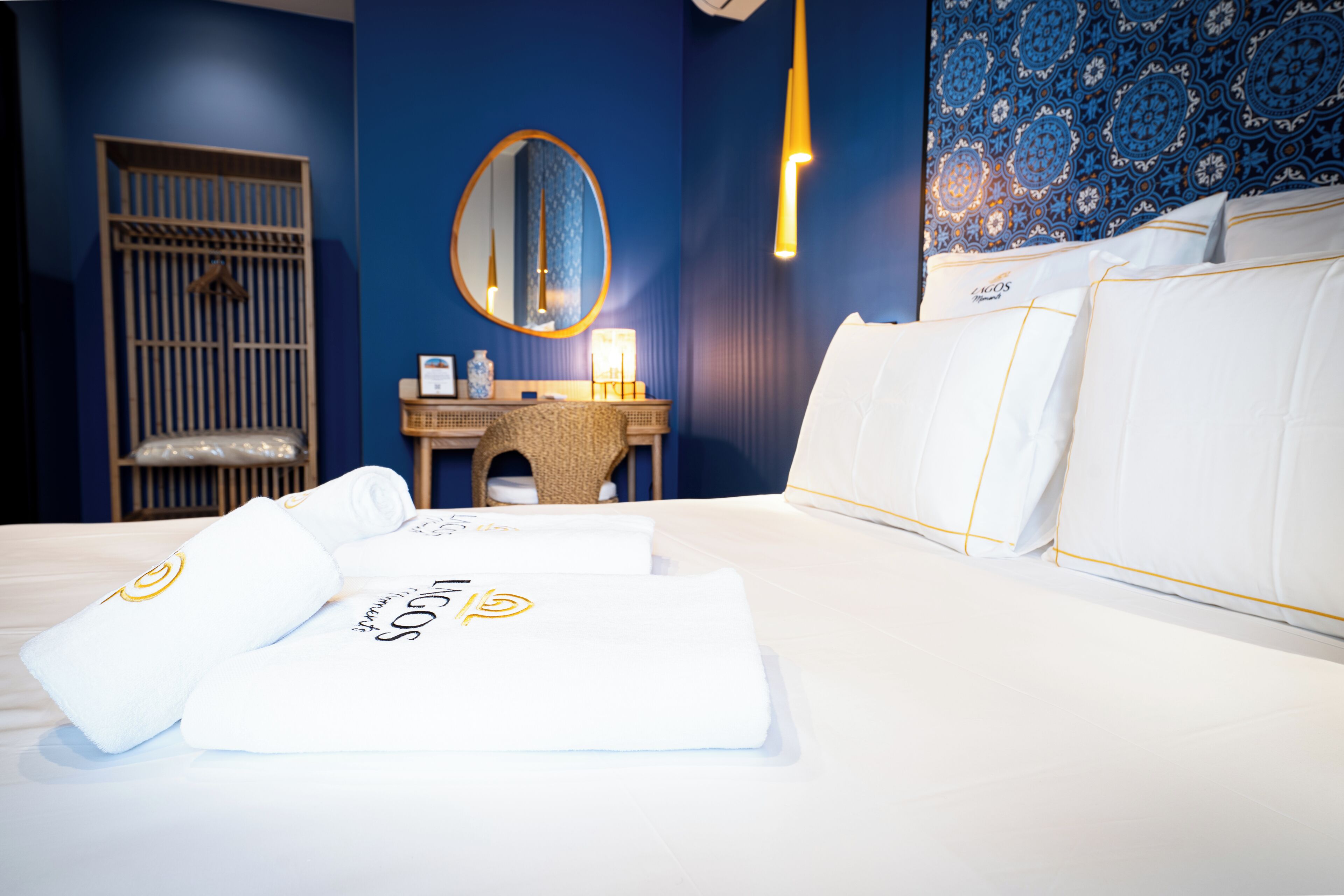 Una camera d'albergo con un letto, un comodino, uno specchio, una parete con motivo decorativo e una culla.