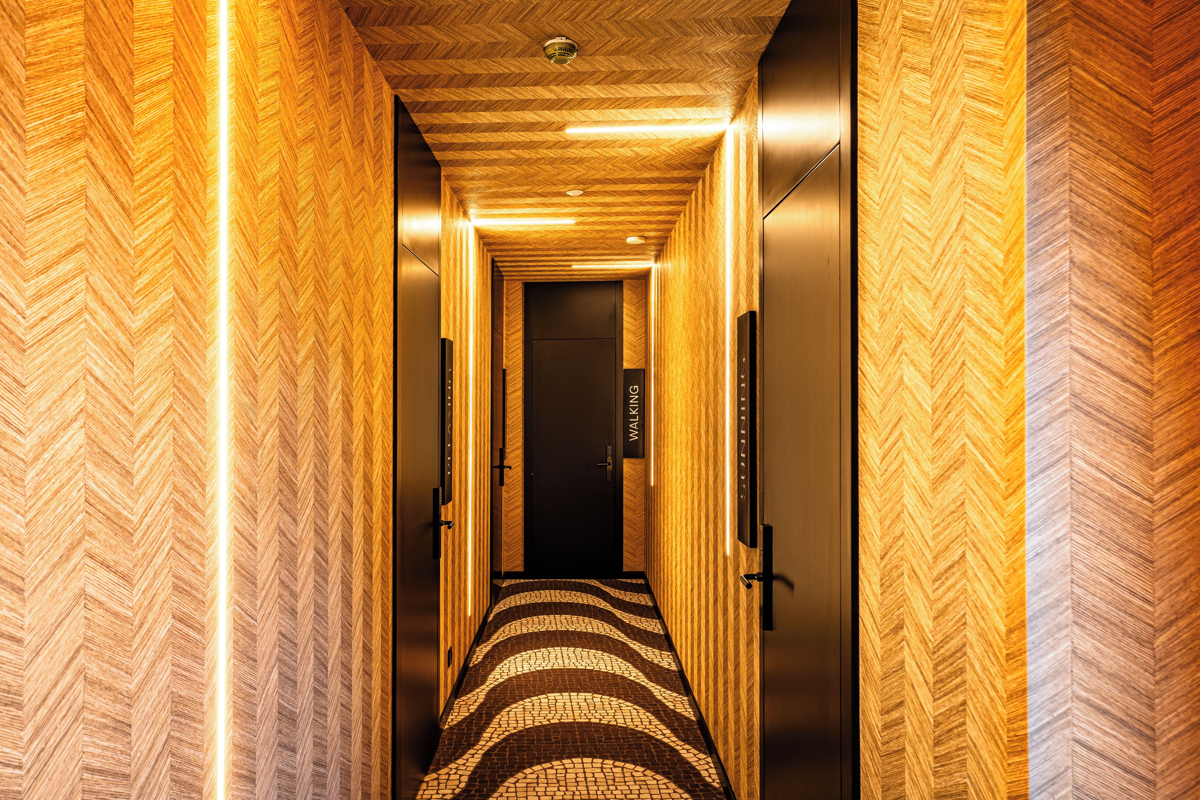 Um corredor com parede em padrão herringbone e tapete estampado.