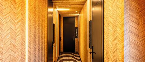 A hallway with a herringbone-patterned wall and a patterned carpet.