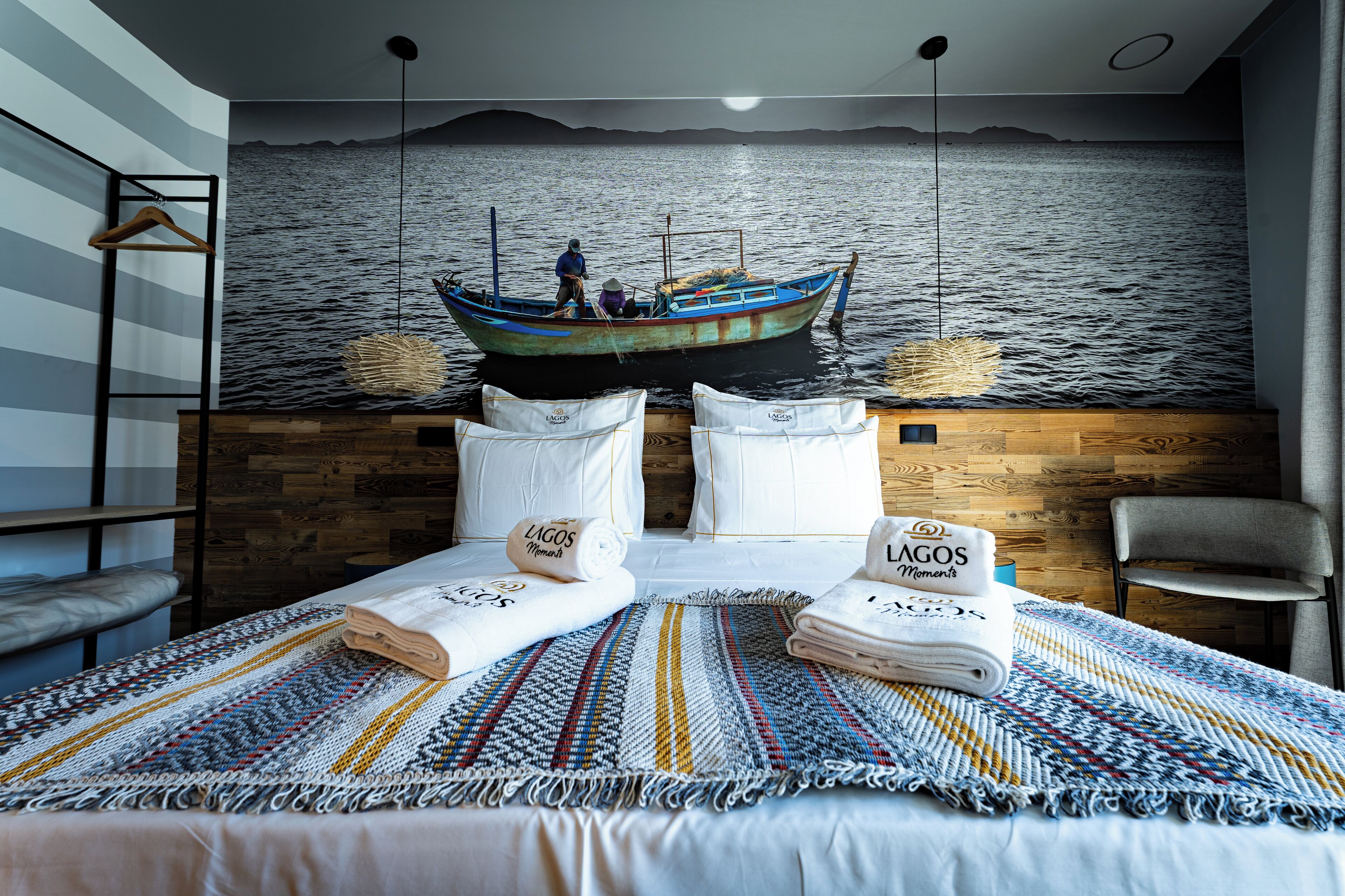 A hotel room with a bed, a view of a boat on the wall, and a wooden headboard.
