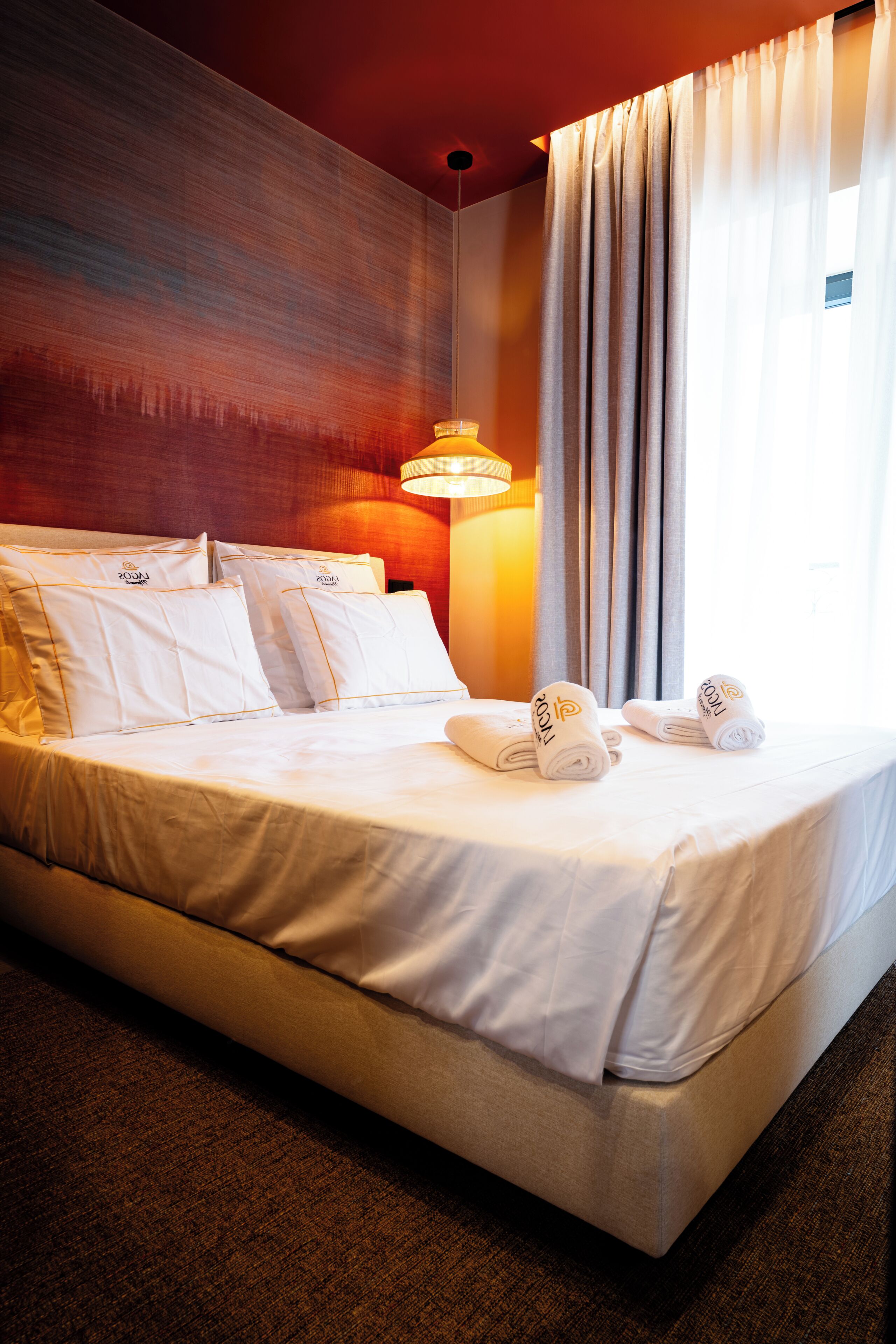 Une chambre d’hôtel avec un grand lit, une lampe de chevet et une fenêtre avec des rideaux.