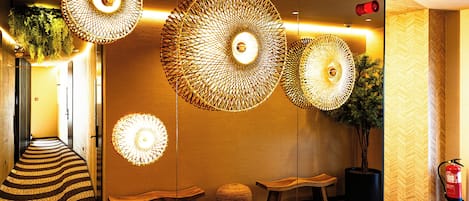 Een hal met een patroon in de vloer, meerdere zithoeken en hangende lampen.