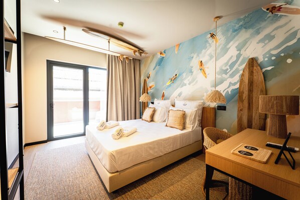 Habitación de hotel con cama, escritorio, silla, un mural en la pared y ventana.