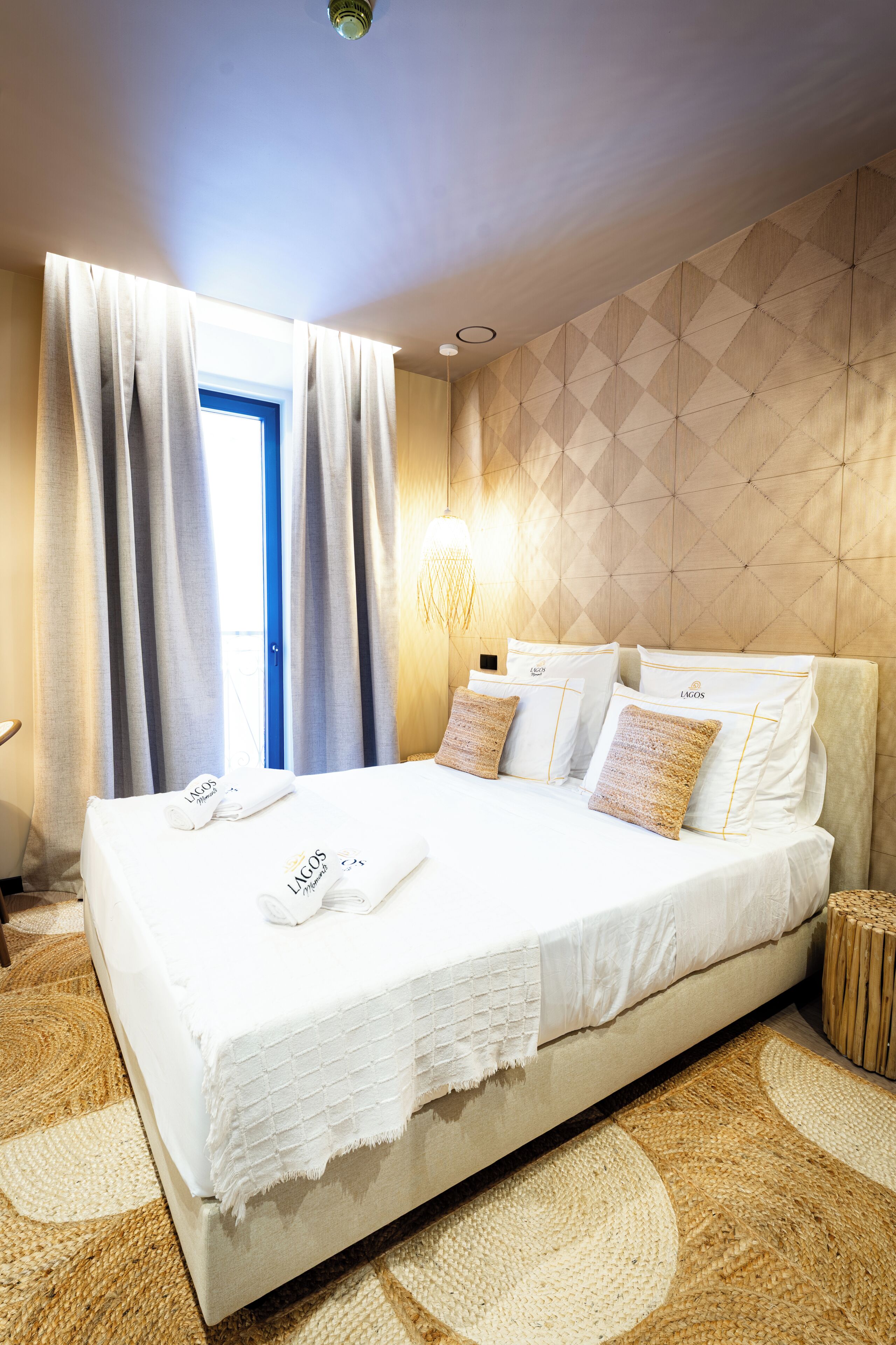 A hotel room with a large bed, a wall-mounted light, and a window with curtains.