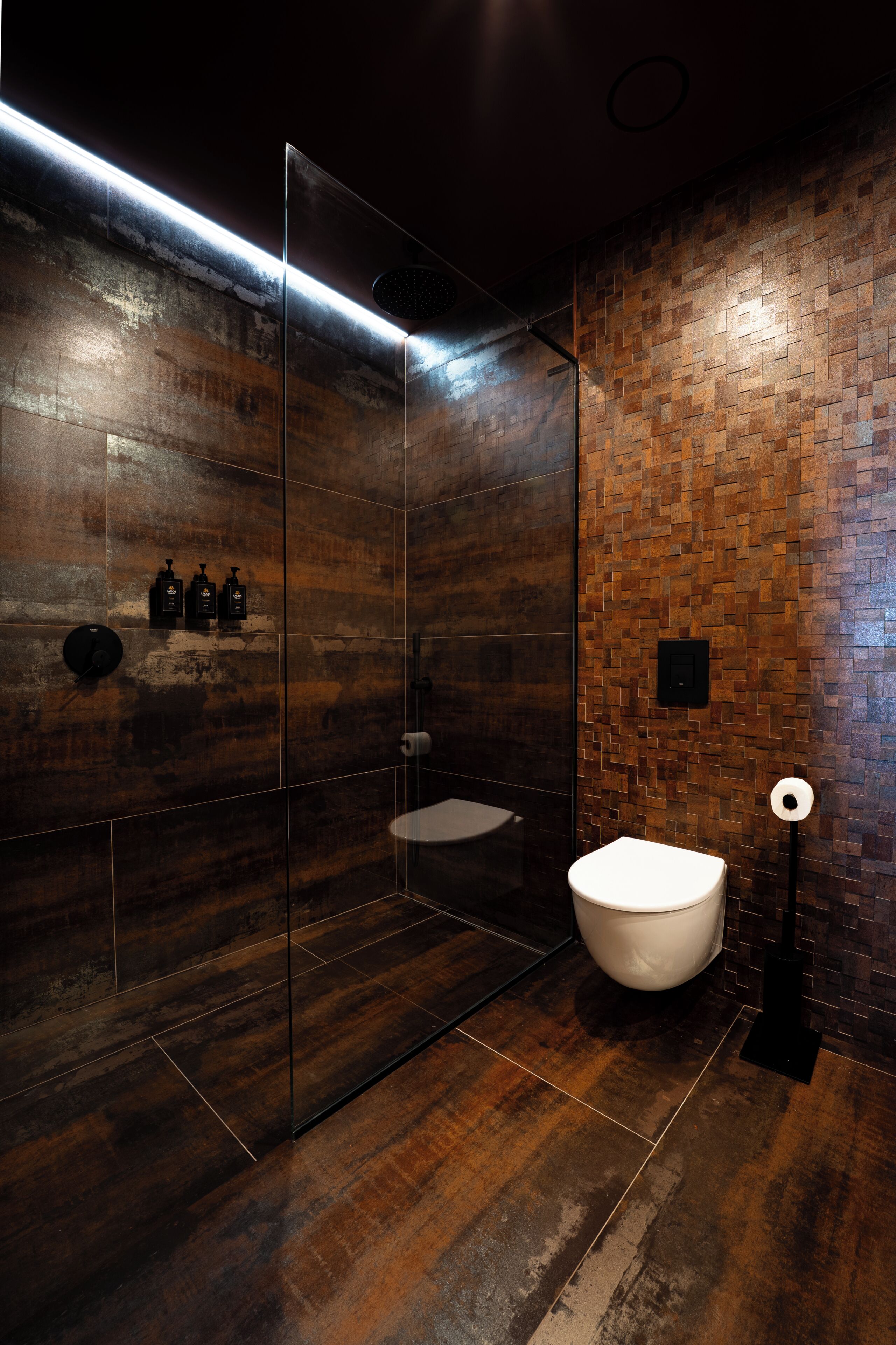 A modern bathroom with a glass shower enclosure, a freestanding bathtub, and a wooden wall design.