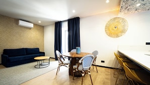Ein modernes Wohnzimmer mit einem dunkelblauen Sofa, einem Holzesstisch mit Stühlen und einem großen Wandbild.