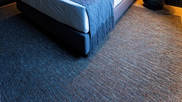 A hotel room with a bed, two bedside lamps, a nightstand, and a wall mural.