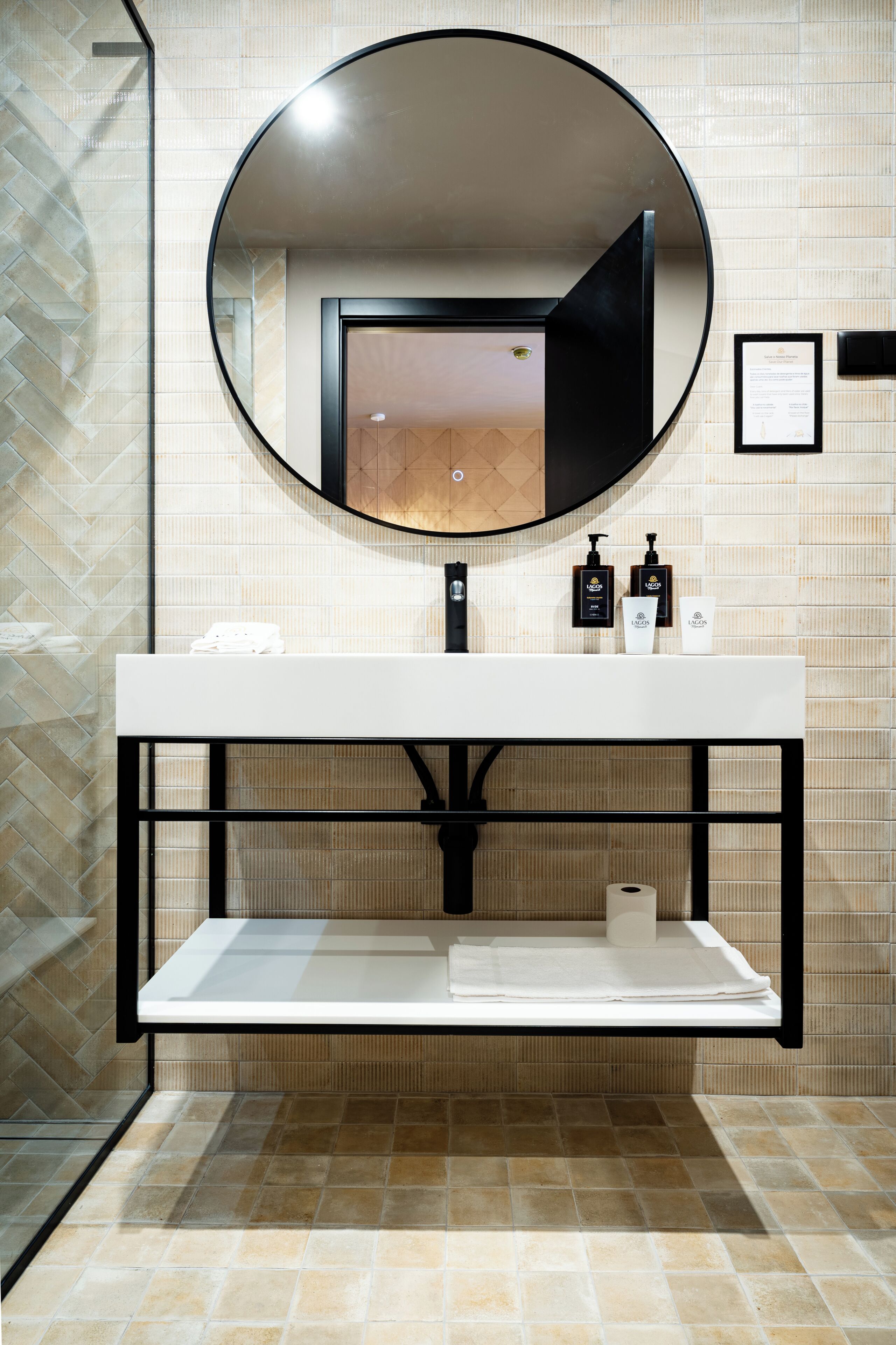 A modern bathroom with a round mirror, a white sink, and toiletries.