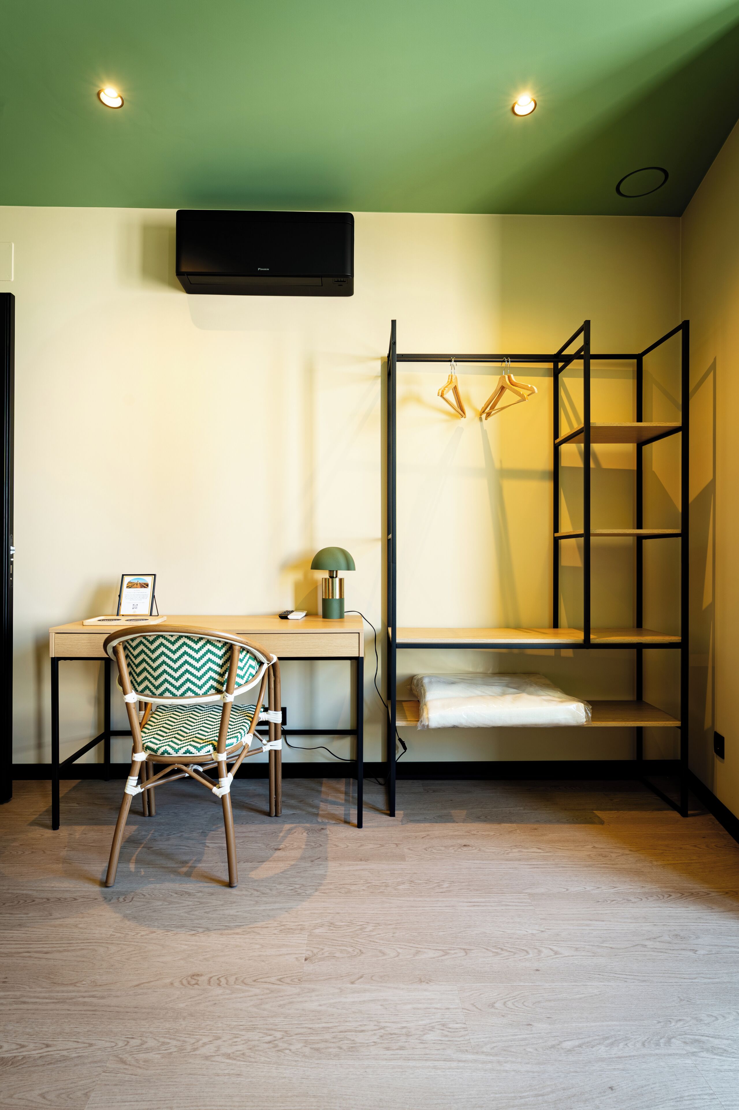 A room with a bunk bed, a desk, a chair, a lamp, and a flat-screen TV mounted on the wall.