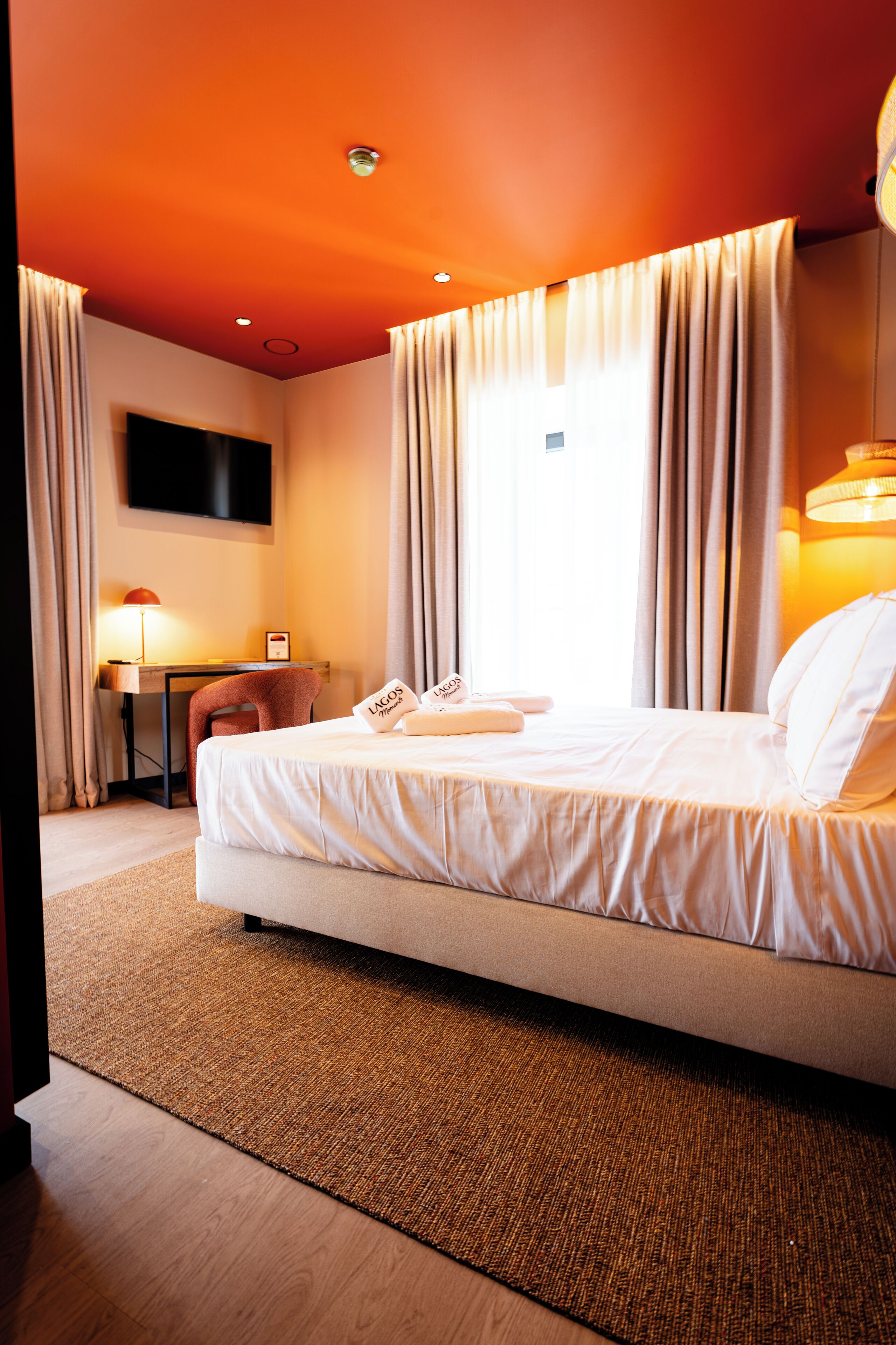 Ein Hotelzimmer mit einem großen Bett, einem Schreibtisch, einem Stuhl und einem an der Wand befestigten Fernseher.