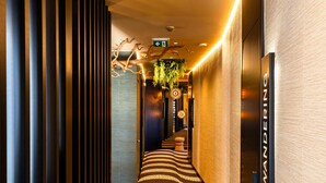 Ein Hotelkorridor mit einem gemusterten Boden, vertikalen Jalousien und einem Schild mit der Aufschrift 'WANDERING'.