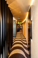 A hotel corridor with a patterned floor, vertical blinds, and a sign reading 'WANDERING'.
