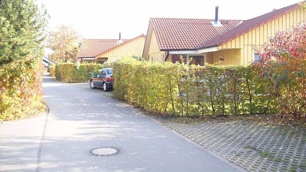 A residential street with houses, a car parked on the side, and a manhole cover on the road. - Schoner Doppelbungalow mit Terrasse im Ferienpark Mirow (Mirow)