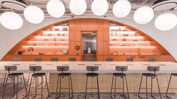 A modern bar area with a curved counter, multiple stools, and a display of various items on shelves.
