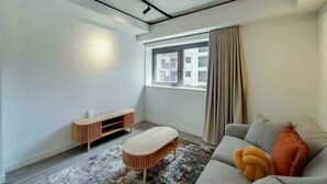 Una sala de estar moderna con un sofá, una mesita de madera y un tapete estampado.
