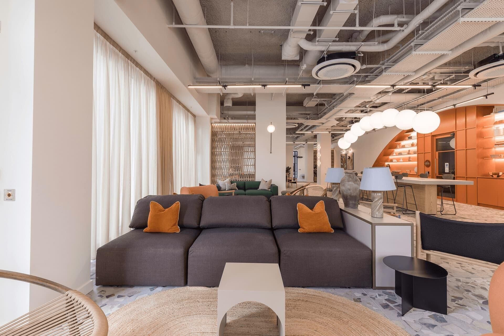 A modern interior with a sectional sofa, a round coffee table, and a bar area with stools.